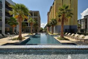 a swimming pool with palm trees in a building at Elegant Modern Studio mins from Riverwalk in San Antonio