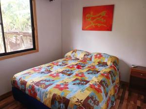 1 dormitorio con 1 cama con un edredón colorido en LA CABAÑA IDEAL PARA FAMILIAS DE 6 a 12 PERSONAS!, en Hanga Roa