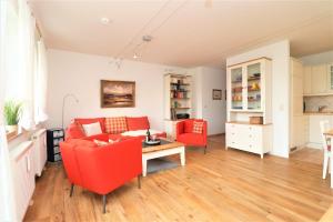 a living room with a red couch and a table at Wohnpark Strandstraße App 12 in Wustrow +2 photos