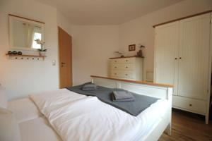 a bedroom with a white bed with a shirt on it at Wohnpark Strandstraße App 12 in Wustrow