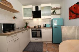 eine Küche mit einem blauen Kühlschrank und weißen Schränken in der Unterkunft Wohnpark Strandstraße App 13 in Wustrow