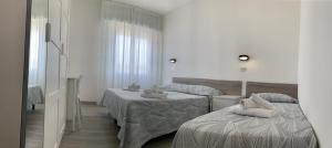 リミニにあるホテル ライカのベッド2台と鏡が備わるホテルルームです。