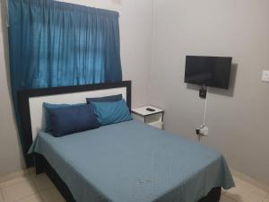 a bedroom with a bed with blue sheets and a television at Mavundla lifestyle lodge in Empangeni