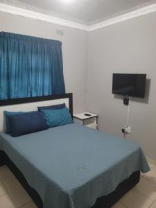 a bedroom with a bed with blue pillows and a television at Mavundla lifestyle lodge in Empangeni