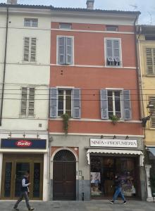 dos personas caminando en frente de un edificio en Repubblica90 eleganza e confort, en Parma