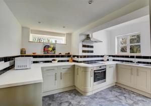 eine große Küche mit weißen Schränken und weißen Geräten in der Unterkunft Rose Cottage in Stiffkey