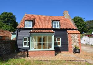 ein schwarzes Haus mit orangefarbenem Dach in der Unterkunft Rose Cottage in Stiffkey