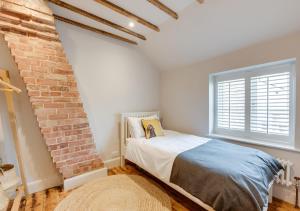 a bedroom with a bed and a brick wall at Peacock Cottage in Holt