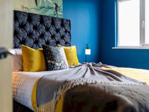 una camera da letto con letto, cuscini gialli e pareti blu di Pass the Keys Central One bed apartment a Nottingham