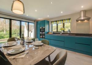 a dining room with a table and some blue cabinets at Peaty Cottage in Panxworth