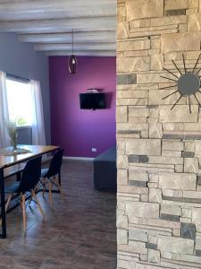 a dining room with a table and a stone wall at Cabañas Los Mochuelos in Villa Cura Brochero