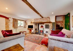 a living room with two couches and a fireplace at Reclaim Cottage in Colkirk