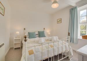 a bedroom with a white bed with blue curtains at Reeve Cottage in Blakeney