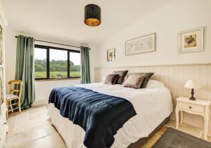 a bedroom with a large bed and a window at Roe Deer Barn in Briston