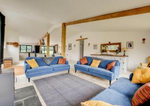 a living room with two blue couches and a table at Roe Deer Barn in Briston
