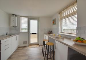 a kitchen with white cabinets and a counter top at Sailing Club Bungalow in Wolferton
