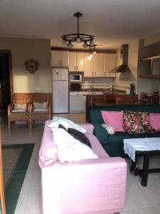 ein Wohnzimmer mit einem rosa Sofa und einer Küche in der Unterkunft Los Rosales de Gredos in Hoyos del Espino