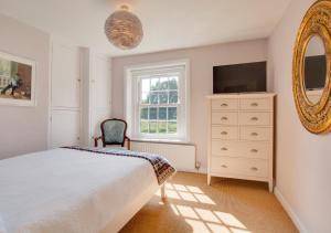 a bedroom with a bed and a dresser and a mirror at South Cottage in Antingham