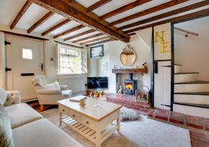 a living room with a fireplace and a table at Robin Cottage in North Elmham