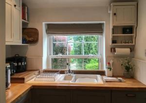 a kitchen counter with a sink and a window at Poppy Cottage in Stiffkey