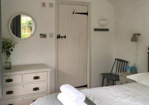 a bedroom with a bed and a mirror and a dresser at Poppy Cottage in Stiffkey