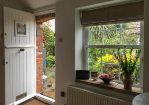 a kitchen with a window and a bowl of fruit on a window sill at Poppy Cottage in Stiffkey