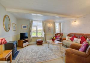 a living room with a couch and a tv at Shamrock Cottage in Hindringham