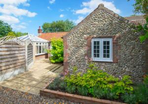 a stone house with a garden and a fence at Sunset Cottage in Hickling