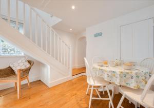 a white dining room with a table and chairs at Silvergate Cottage in West Runton