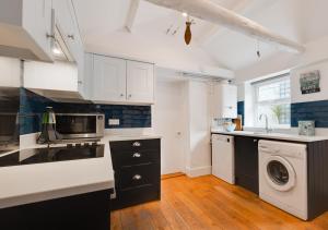 a kitchen with white cabinets and a washer and dryer at Silvergate Cottage in West Runton