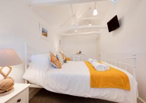 a bedroom with a white bed with a yellow blanket at Silvergate Cottage in West Runton