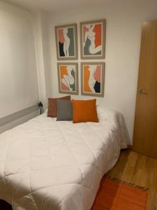a large white bed in a room with pictures on the wall at ALOJAMIENTO SARDOY in Murcia