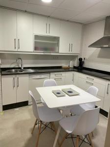 a kitchen with a white table and white chairs at ALOJAMIENTO SARDOY in Murcia