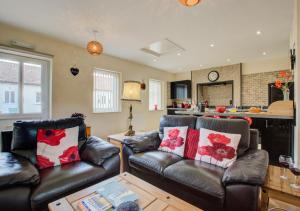 a living room with two leather couches and a kitchen at Smithy Cottage in Blofield