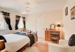 a bedroom with a bed and a chair at Smithy Cottage in Blofield