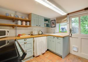 una cocina con armarios de color verde menta y una ventana en Sky Cottage, en Worstead
