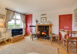 a living room with a fireplace and a television at Sky Cottage in Worstead