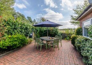 a patio with a table and chairs with an umbrella at Sandy Bottom in Hunstanton