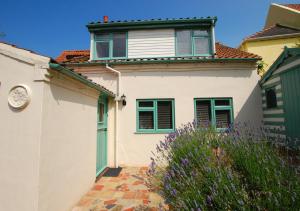 uma casa branca com uma porta verde e flores roxas em Smugglers Retreat em Wells-next-the-Sea