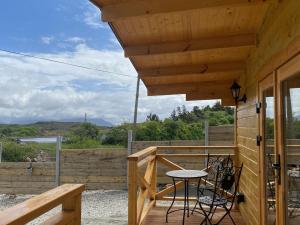 un porche de una cabaña de madera con mesa y sillas en Cabin 438 - Clifden en Clifden