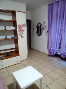 sala de estar con cortinas moradas y mesa blanca en Fiuggi Appartamento Turistico en Fiuggi