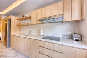 a kitchen with wooden cabinets and a sink at Lumina at Cardinal San José del Cabo in San José del Cabo