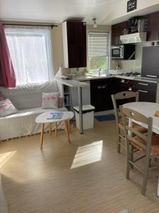 una piccola cucina e soggiorno con un divano e un tavolo di MOBIL HOME 3 chambres, 6 couchages, RAMATUELLE ST TROPEZ, PLAGE DE PAMPELONNE a Saint-Tropez Altre 20 foto