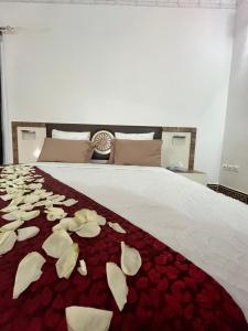 a bed with white flowers on a red blanket at Haramous Guest House in Djibouti