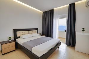 a bedroom with a large bed and a large window at Hotel Eleana & Apartments in Sarandë