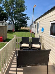 two chairs sitting on a deck next to a trailer at Luxury 8 and 6 berth caravans in Jaywick Sands