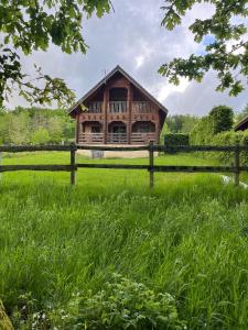 ein Holzhaus auf einem Feld mit einem Zaun in der Unterkunft Au bord du lac III in Montigny-en-Morvan