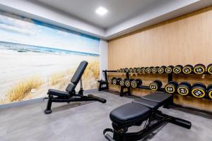a gym with two chairs and a view of the beach at Apartament Olive Rewal z dostępem do basenu in Rewal
