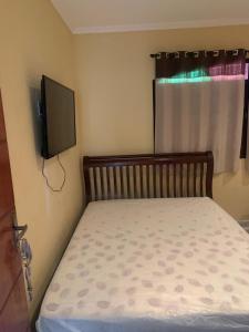 um quarto com uma cama e uma televisão na parede em Casa de Veraneio em Maricá