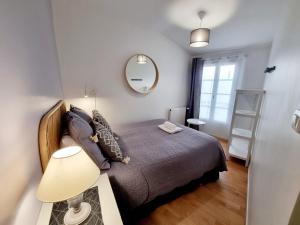 um pequeno quarto com uma cama e um espelho em Coquette maison de ville calme avec patio em Angoulême